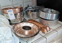 Stack of Bundt pans, angel food pans, egg beater, fish mold on countertop