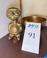 Front view of brass ET figurine beside brass bowl