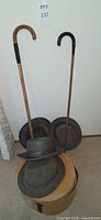 Group shot of two canes, four hats and hat box