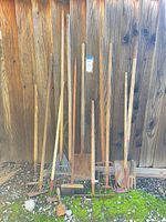 Group shot of all long-handled tools leaning against fence