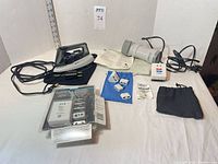 Group shot of iron, steamer, converter kit, loose adapters, converter block and pouch