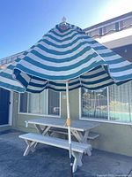 Full view of striped patio umbrella over picnic table and benches