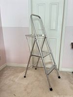 Full view of folded aluminum 2-step ladder with handrail and rubber feet