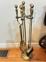 Full view of brass fireplace tool set on stand