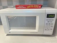 Front view of white GE microwave with boxed hot plate on top