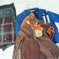 Mix of blue Girl Guides jackets, brown Brownies jacket, tartan skirts, beret, belt, scarf
