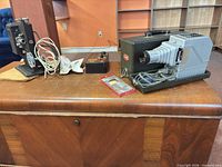 Two projectors, control box, film reel sleeve and cables on table