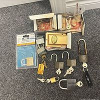 Overall lot showing boxed rim lock sets, blister-packaged padlock, loose padlocks and keys on carpet