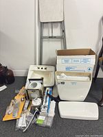 Group shot of toilet tank, lid, sink, faucet parts, light globe, plumbing parts, stool, fluorescent tube