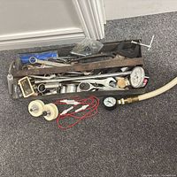 Top view of full metal tray with assorted hand tools, gauges, pulleys, leads