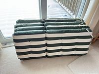 Four stacked green and white striped cushions showing front and side profile