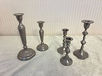 All five pewter-tone candlesticks grouped