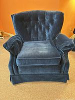 Front view of dark navy velvet Sklar-Peppler armchair showing tufted back, rolled arms and skirted base