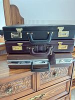 Stacked view of three briefcases showing exteriors and hardware