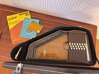 Autoharp inside open hard case with three songbooks