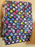 Stack of nine polka dot drawstring backpacks in clear plastic packaging.