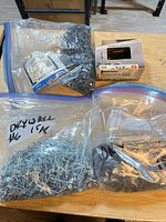 Bags and box of mixed drywall screws and nails on table