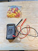Multimeter with test leads and bag of connectors on table