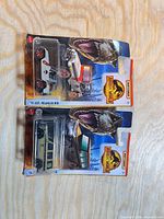 Front view of two Hot Wheels Jurassic Park series vehicles in sealed blister packs