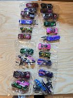 Eight sealed plastic bags, each with three Hot Wheels vehicles, laid out on table