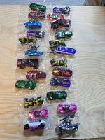 All 24 sealed Hot Wheels vehicles arranged in eight groups of three on table