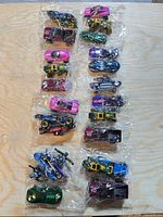 Eight unopened Hot Wheels three-packs containing assorted vehicles laid out