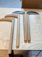 Four kama laid out showing two all-wood and two metal-head models