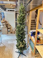 Full view of assembled pencil Christmas tree with bottom lights illuminated