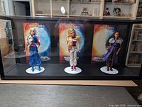 Front view of three dolls in acrylic display case
