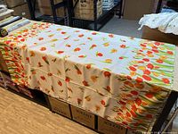 Rectangular white tablecloth with red-orange tulip print placed on boxes
