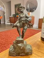 Full view of figurine on rock base showing posture and costume