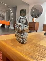 Front view of soapstone carving of hooded fisherman with seal on base