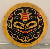 Front view of round wooden art panel with Northwest Coast design and signature