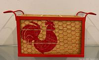 Front view showing rooster graphic, wire mesh, and handles