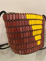 Front and side view showing brown wooden beads with yellow stripe pattern and black braided strap