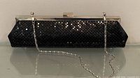Front view of black metal mesh clutch with chain strap displayed