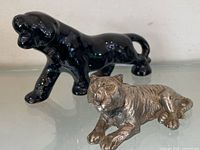 Black ceramic panther standing behind silver-tone metal tiger lying down