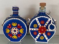 Front view of both leather-wrapped decanters showing motifs and shape