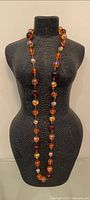 Full view of long glass bead necklace on display form