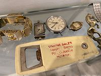 Close-up of bracelet, watches, bottle opener, letter opener