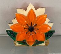 front view showing orange flower, green leaves, clear base