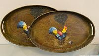 Two oval wooden trays showing fronts with rooster artwork