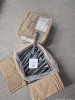 two cardboard cases, one open showing multiple galvanized carriage bolts and one sealed