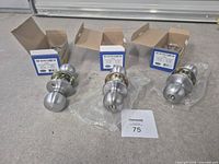 Three boxed satin chrome door knob sets with packaging visible
