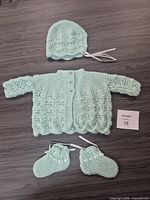 Full view of jacket, bonnet and booties laid flat