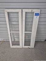 Front view of both salvaged windows showing white painted wood frames and clear glass