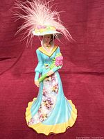 Front view of porcelain lady bell showing dress, hat, bouquet and overall colour scheme