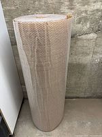 Full view of tall bubble wrap roll leaning against wall