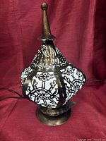 Front view of pierced metal table lamp with finial and cord