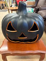 Front view of black pumpkin blow mold showing orange-edged facial cutouts